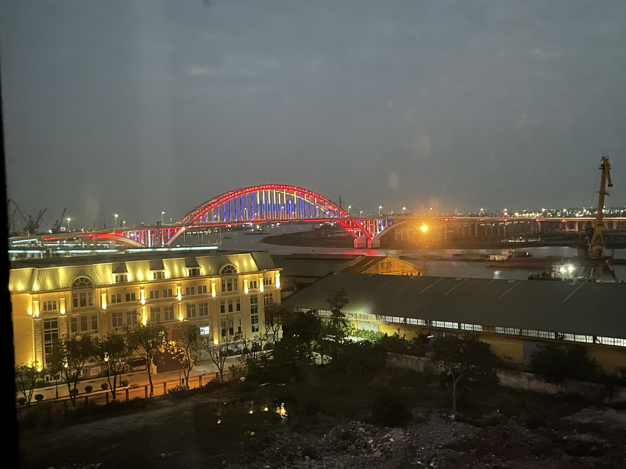 夜のカム川と赤く光るホアンヴァントゥ橋、対岸のクレーン
