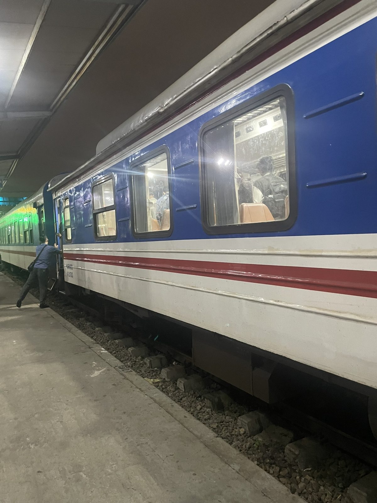 夜の駅のホームに停まる青と白のベトナム鉄道の客車
