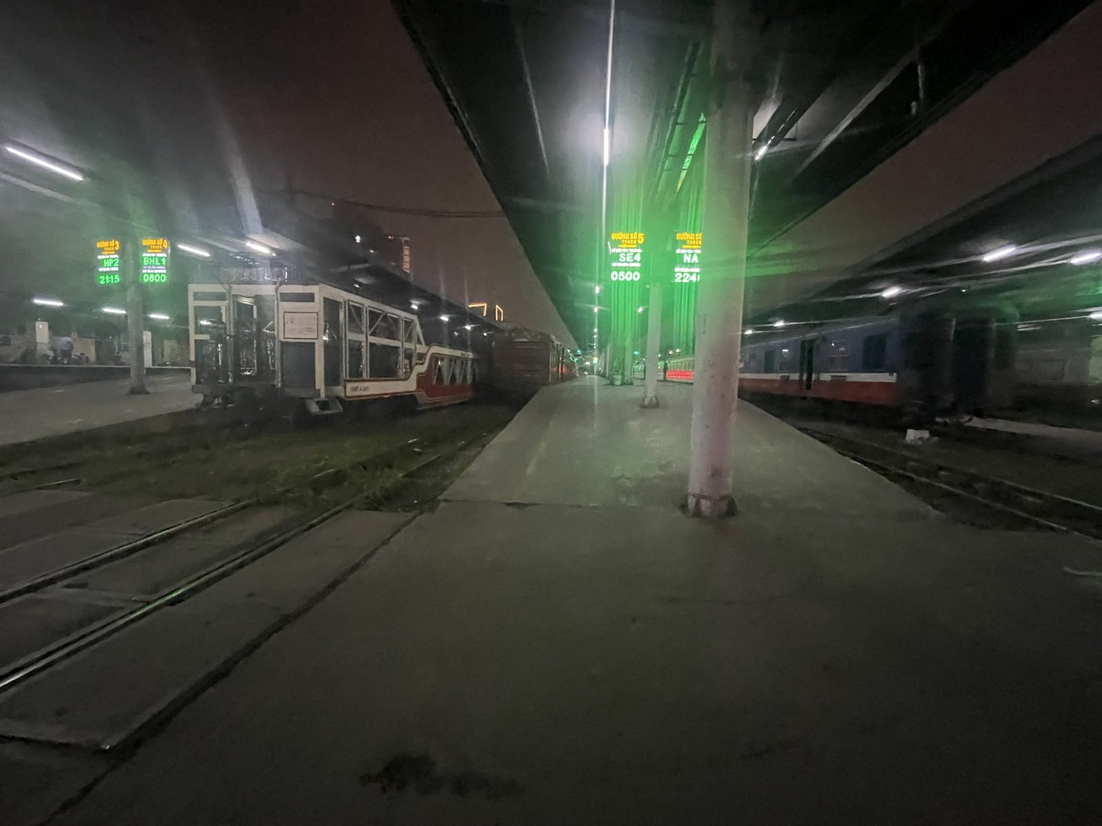夜のハノイの駅構内。複数の線路と緑色の照明