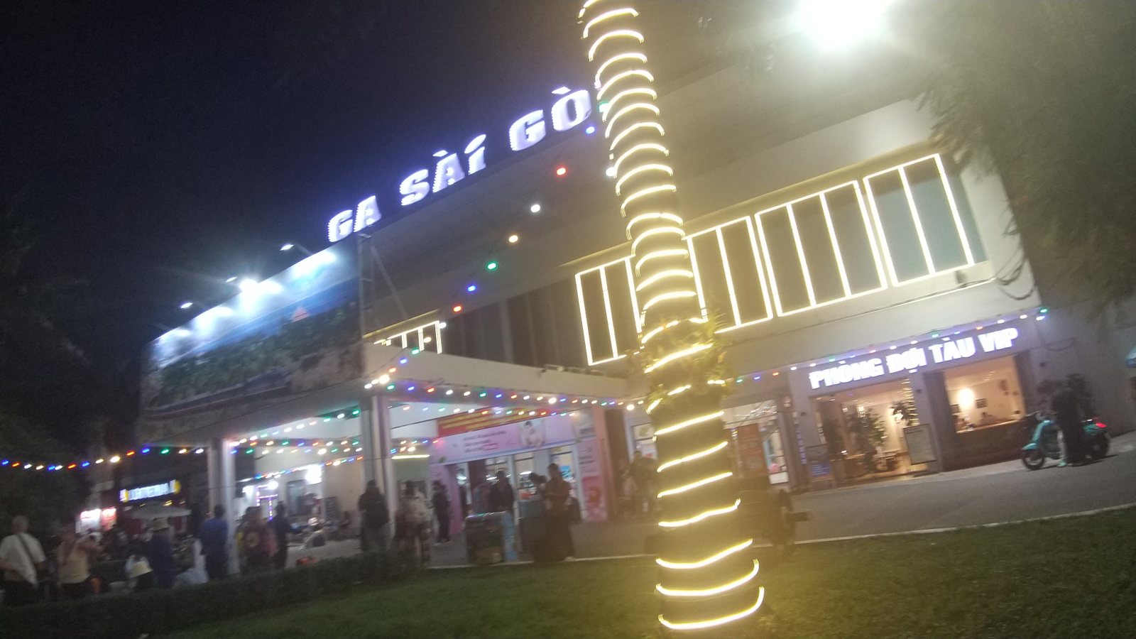 夜のサイゴン駅舎とGA SÀI GÒNの看板、駅前の人々